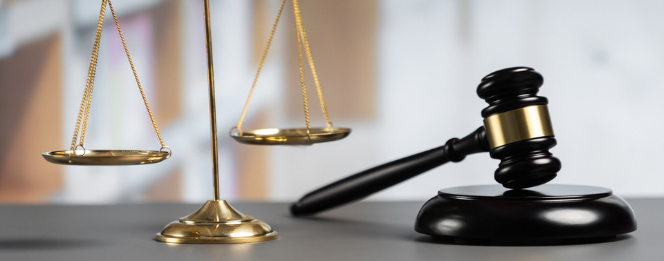 Shiny golden balanced scale and wooden gavel in court library background