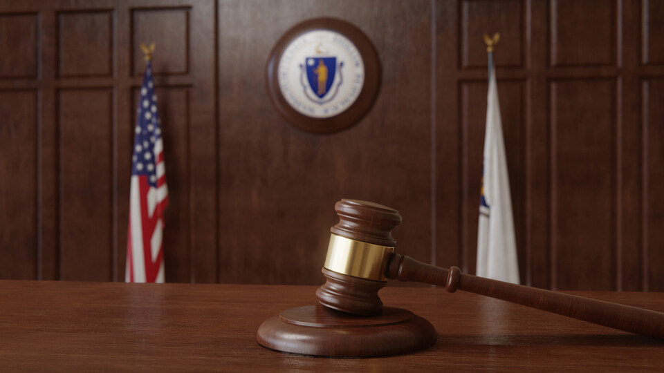 Courtroom scene with US flag and state seal and flag of the state of Massachusetts