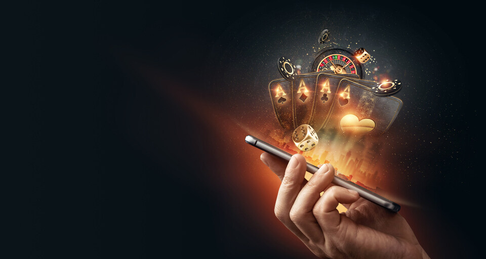 A smartphone with playing cards, roulette and chips, black-gold background