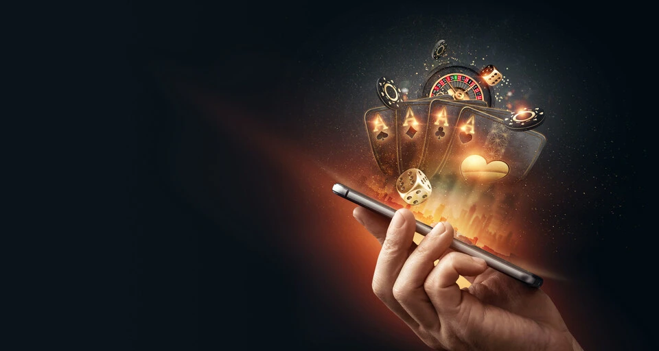 A smartphone with playing cards, roulette and chips, black-gold background
