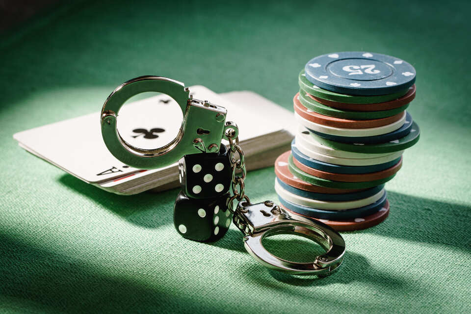 Dice, cards, chips, and handcuffs on the table in hard light