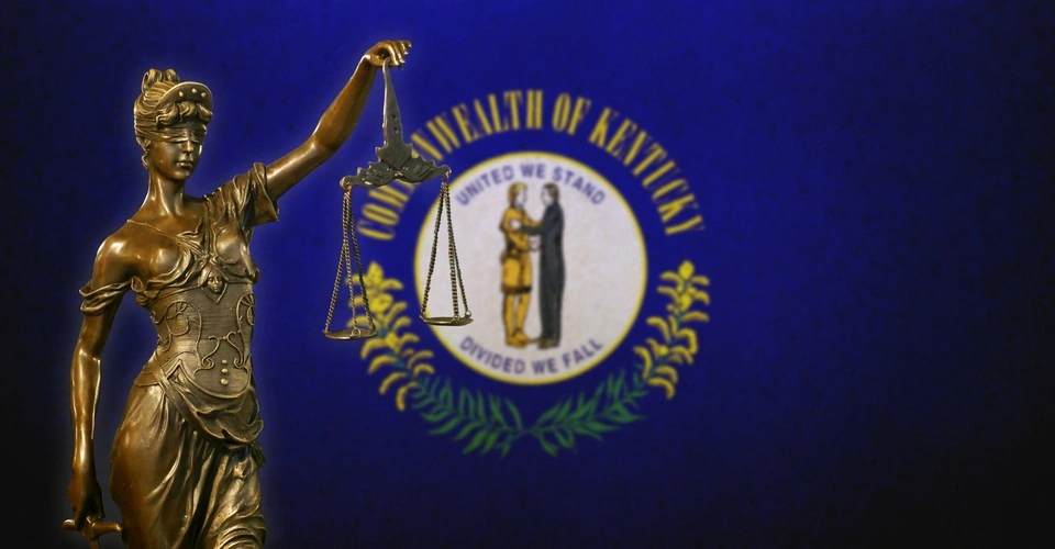 A statue of justice to the left with Kentucky flag and emblem in the background